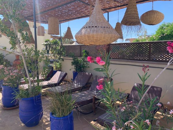 Terrasse fleurie d’un riad avec lanternes en osier